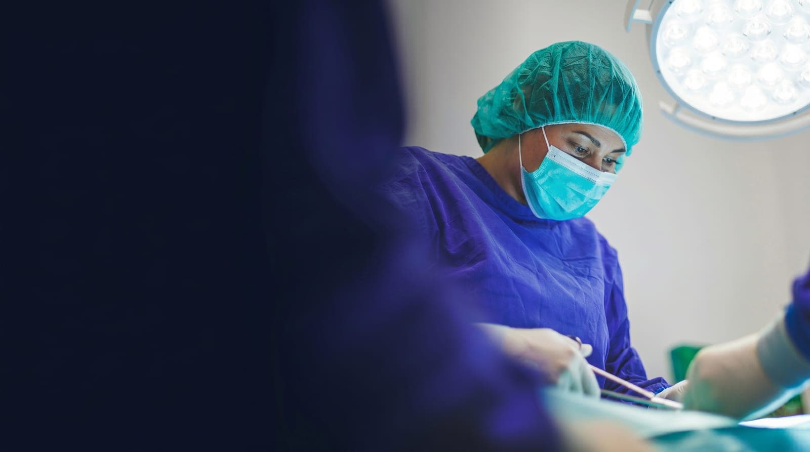 A surgeon in theatre working beneath operating lights